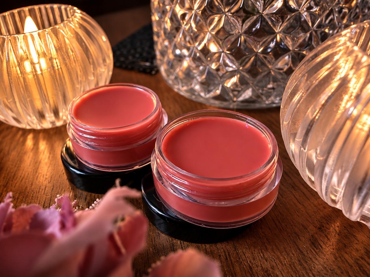 Open tins of natural pink lip balm with rose petals